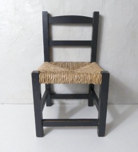 Vintage black wooden child-sized straw chair.