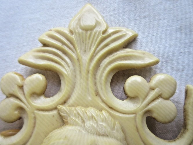 Croix de berceau Art Déco en bakélite beige: Angelot sur acanthes et baies
