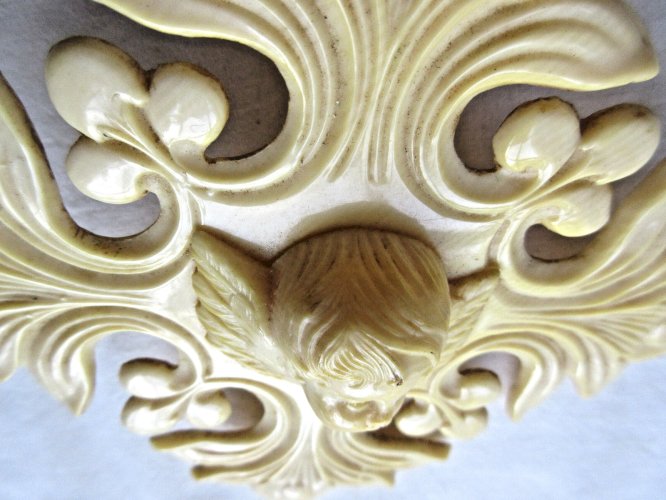 Croix de berceau Art Déco en bakélite beige: Angelot sur acanthes et baies