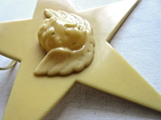 Croix de berceau Art Déco en bakélite beige: Angelot sur étoile à suspendre
