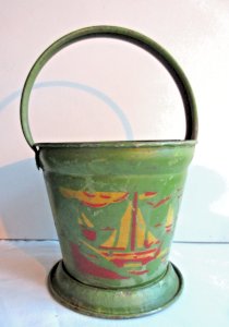 Beach toy from around 1950, green tin bucket decorated with a yellow and red boat.