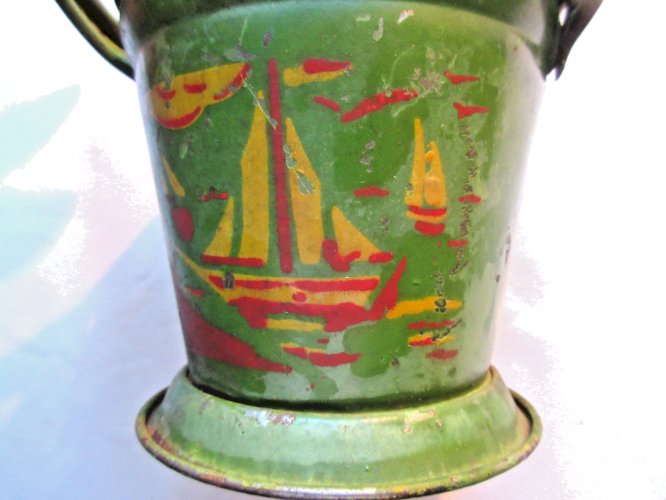Jouet de plage vers 1950, seau vert en tôle décoré d'un bateau jaune et rouge