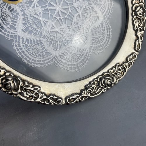 Napperon en dentelle aux fuseaux sous verre cerclé métal argenté décor de roses