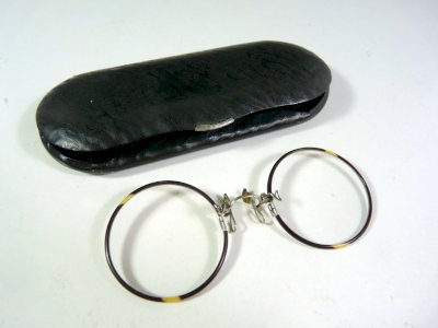 Pairs of lorgnon glasses from the 19th century with round lenses and a black metal case.