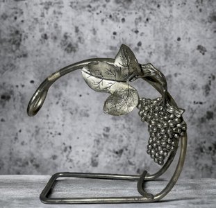 Vintage silver-plated wine bottle holder with vine and grape design.