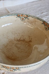 Antique earthenware bowl with green and orange floral decoration.