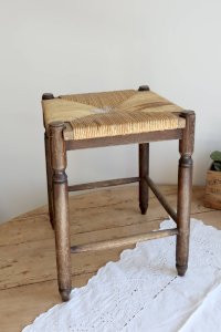 Antique square wooden stool with woven straw seat.