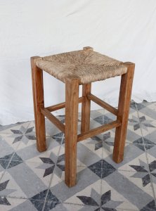 Vintage low stool in rustic wood style with a straw seat.